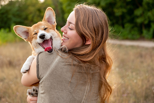 Portrait: young woman with corgi puppy, nature background